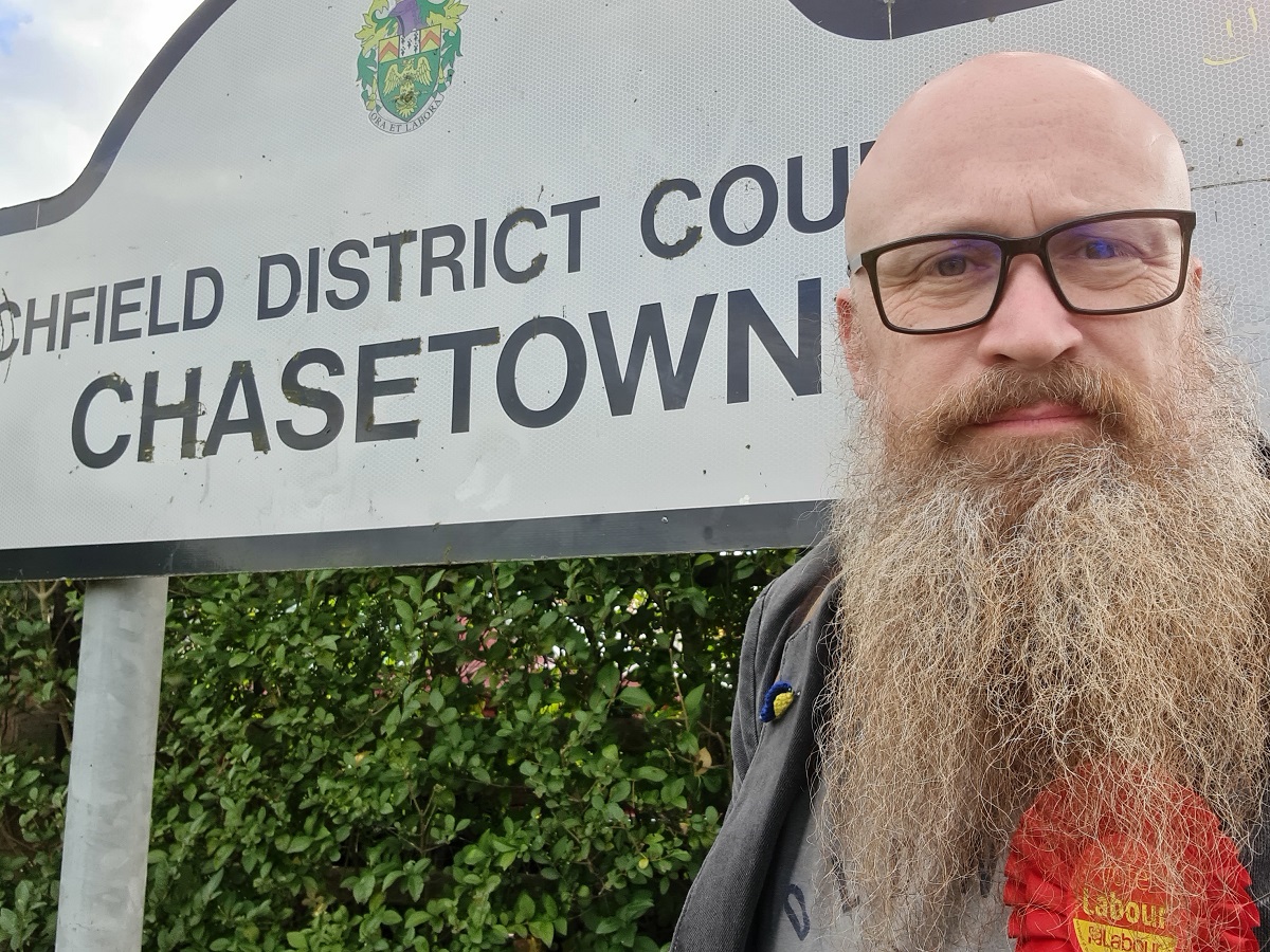 Cllr Paul Taylor in front on a place name sign saying 'Chasetown'